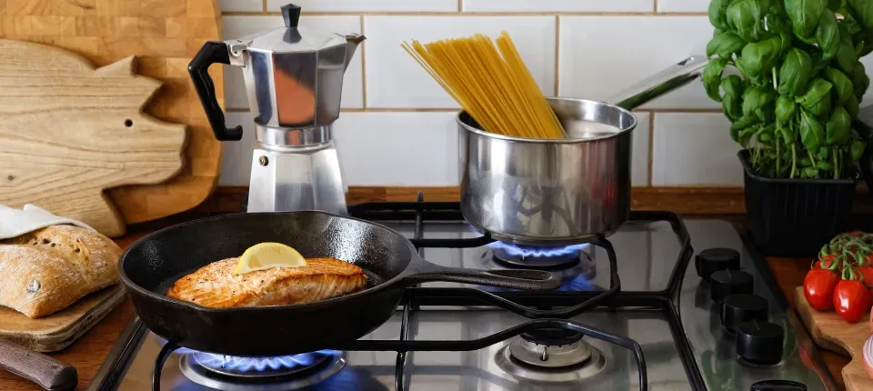 photo of a gas range with salmon and pasta cooking on the stove top